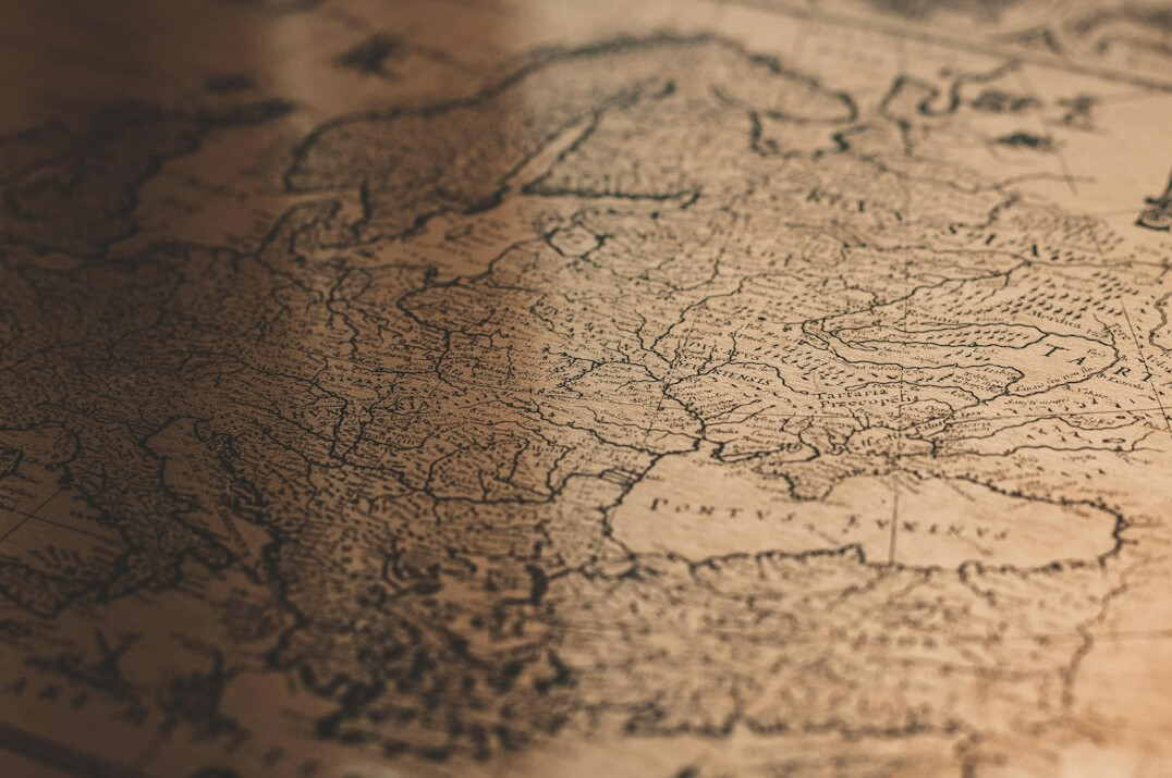 Old map of Uruguay with a brass magnifying glass and pins on a wooden table